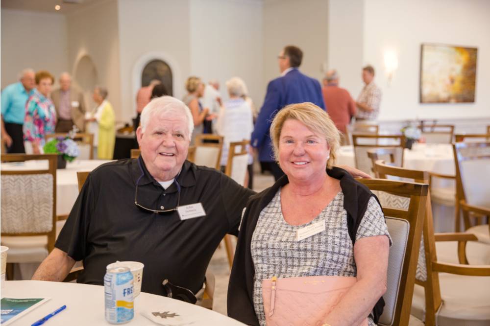 Two guests sitting at a table smiling at Naples 2019